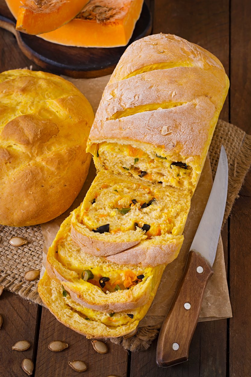 Pães caseiros fatiados sobre tábua de madeira